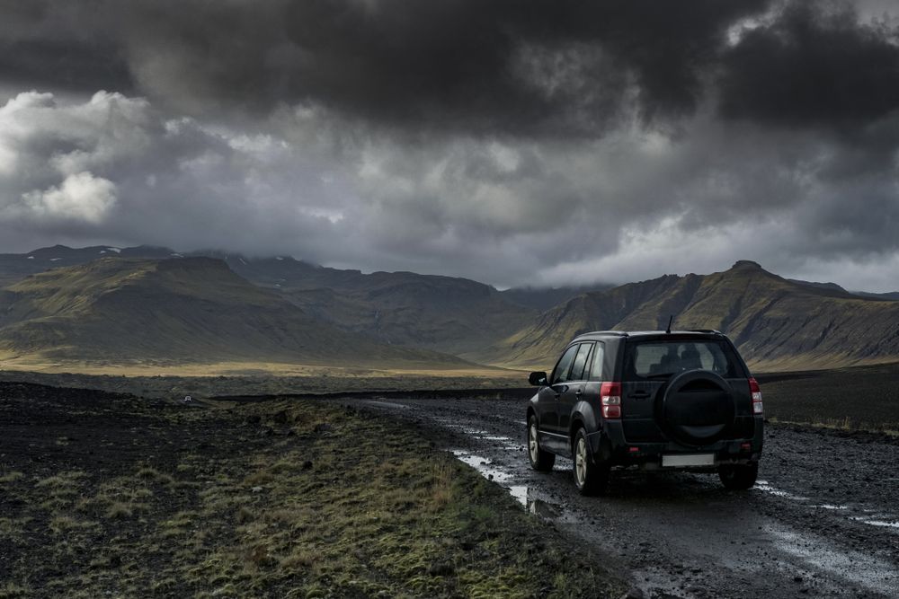 4WD SUV driving into Icelandic mountains under stormy skies