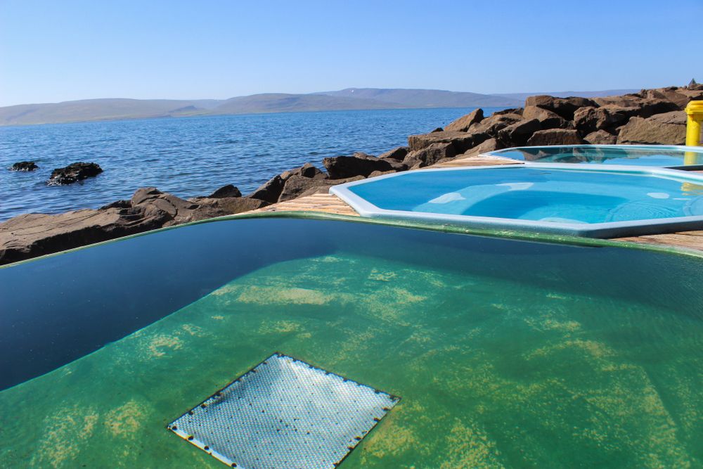 Outdoor geothermal hot tubs by the sea in Iceland, with ocean views and volcanic rocks.