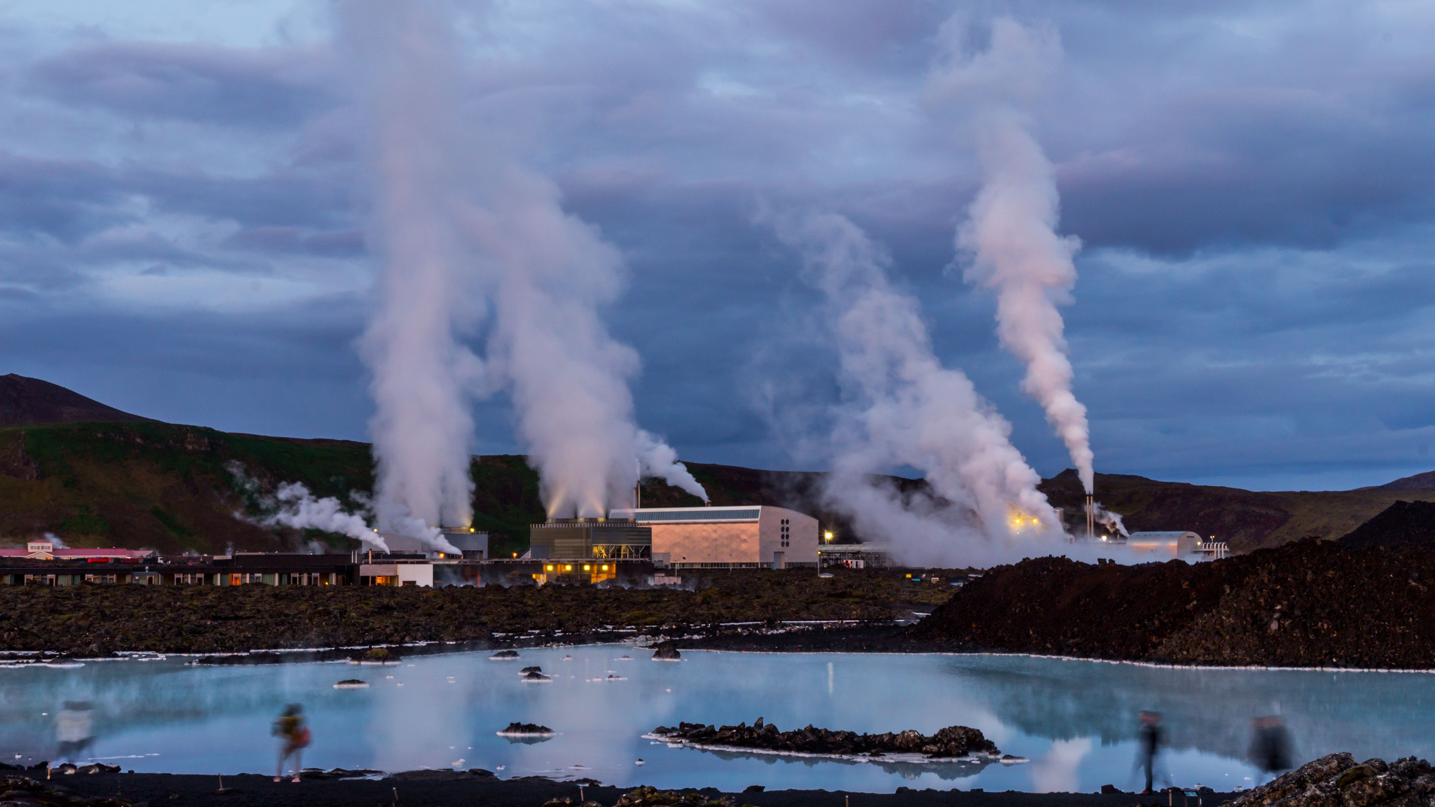 Steam rises from the Svartsengi geothermal power plant beside the iconic Blue Lagoon in Iceland at dusk.