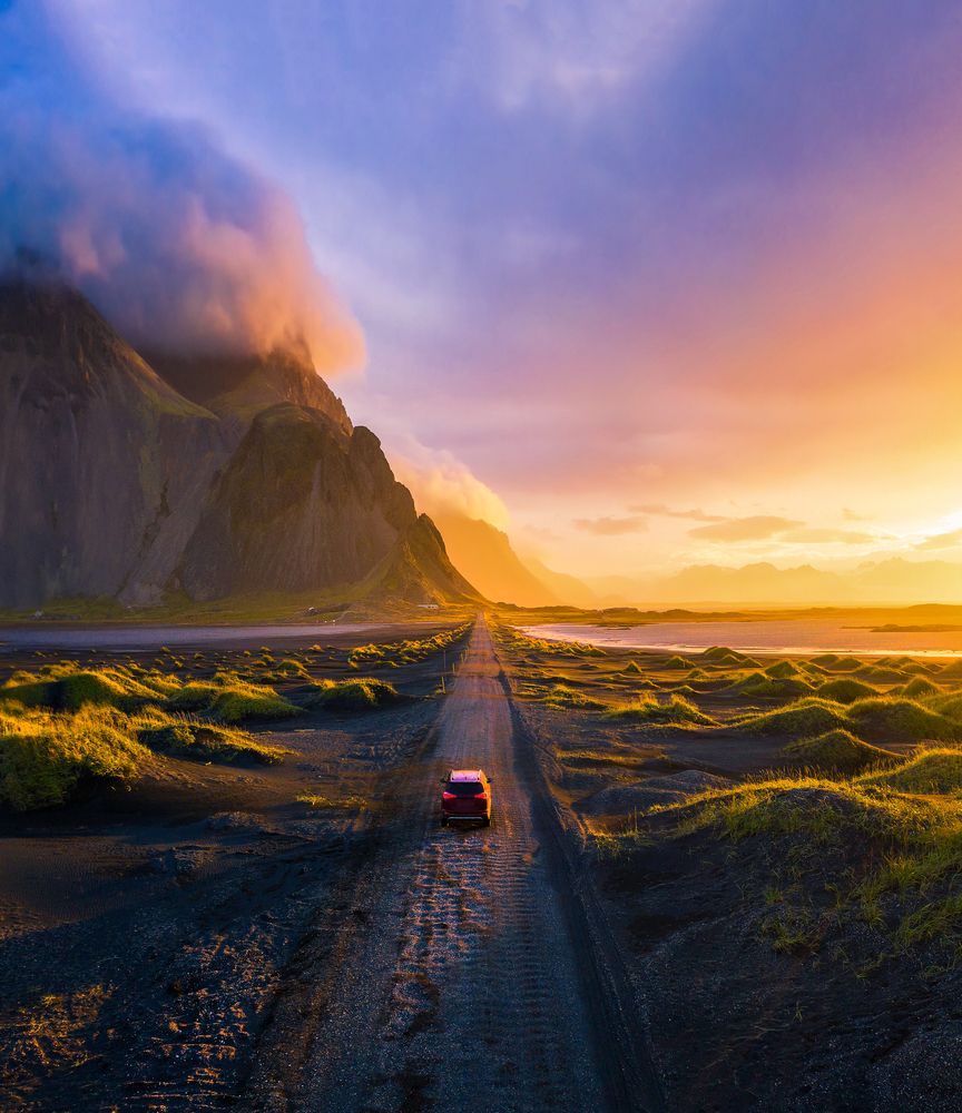 Car driving toward Vestrahorn mountain in Iceland at sunset