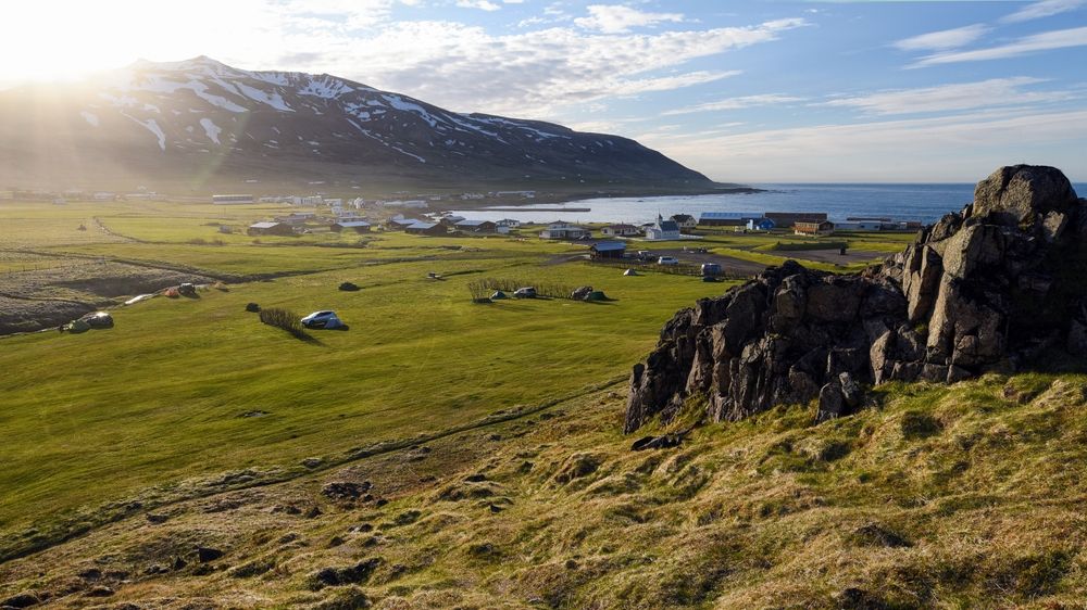 Small village of Bakkagerdi nestled between ocean and snowy mountains in North Iceland