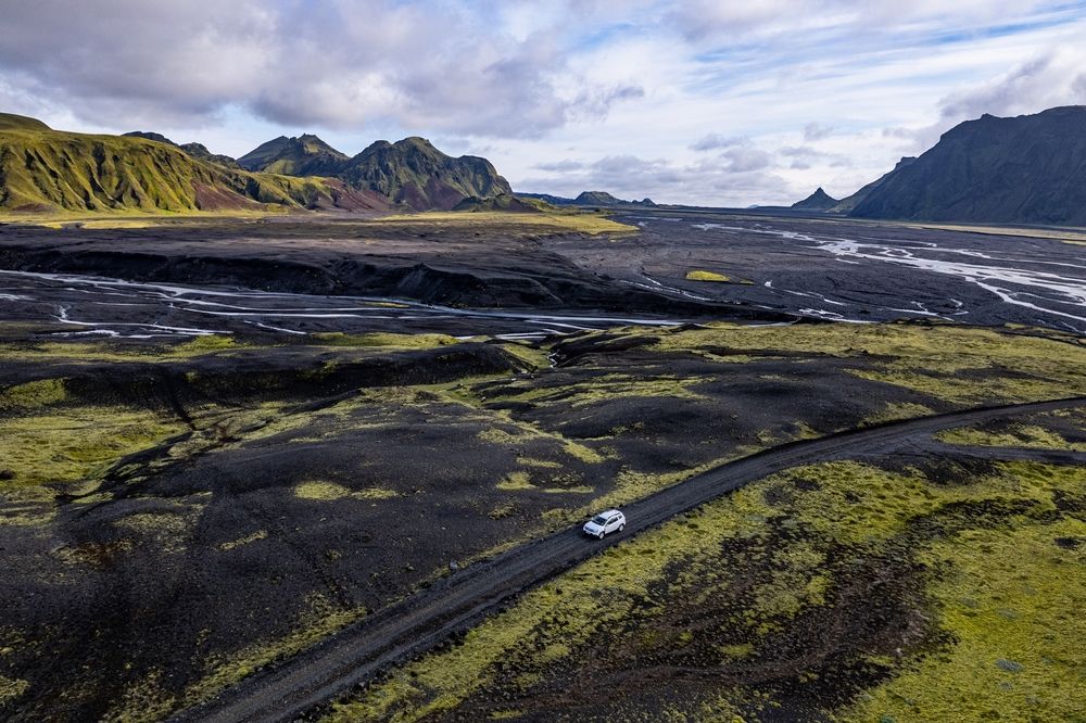 Rental car driving through a remote black sand valley in Iceland