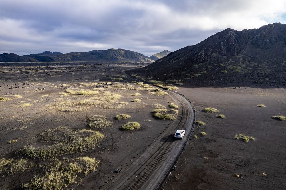 Car driving across volcanic desert landscape in Iceland