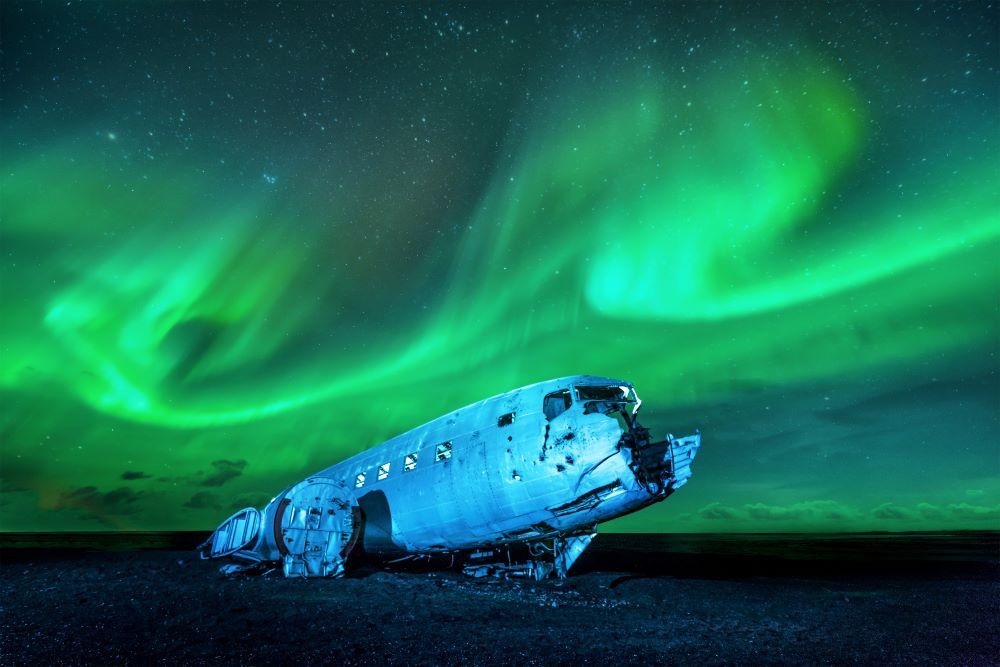 Plane wreck at Sólheimasandur black sand beach under the northern lights in Iceland.