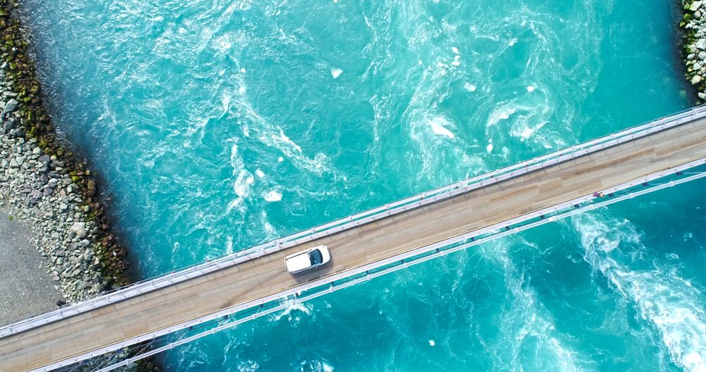 Car driving over a bridge spanning turquoise glacial waters in Iceland of Jokulsarlon